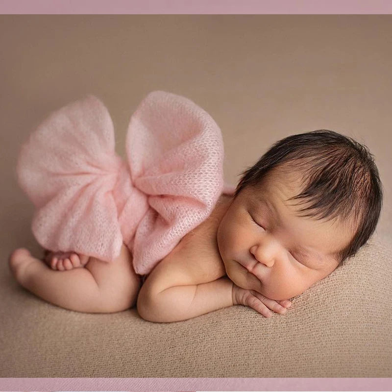 Newborn baby wrapped in pink fabric on a beige background