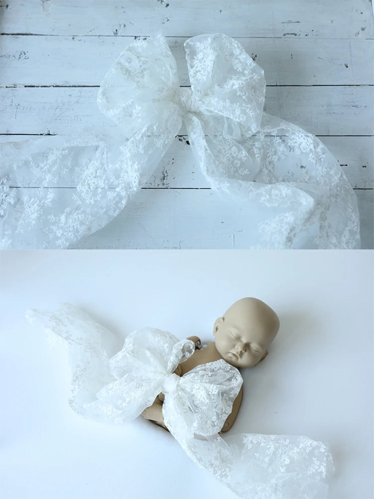 White lace headband and bow with a babydoll on a white wooden surface