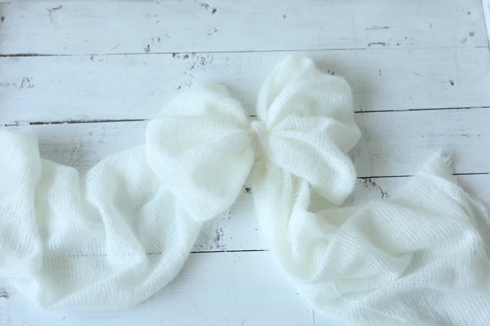 White knitted bow and scarf on a wooden surface