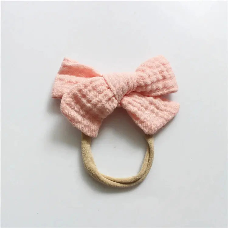 Pink bow-shaped headband on a light gray background