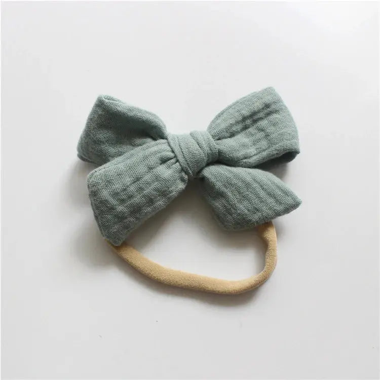 Green textured bow headband on a light gray background