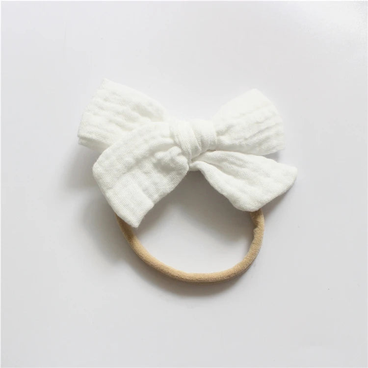 White headband with a large bow on a light gray background