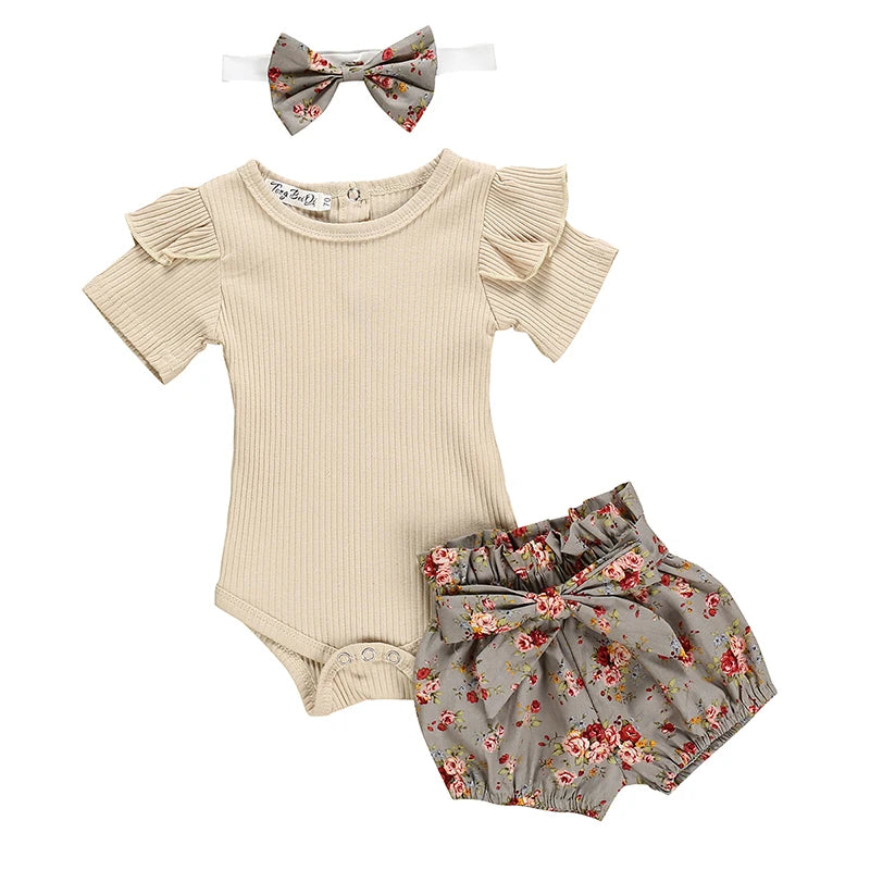 Baby outfit set with beige romper, floral bloomers, and headband on a white background
