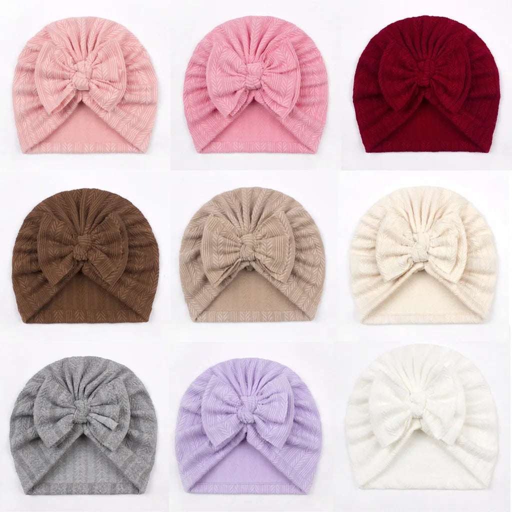 Collection of colorful knitted turbans with bow details on a white background