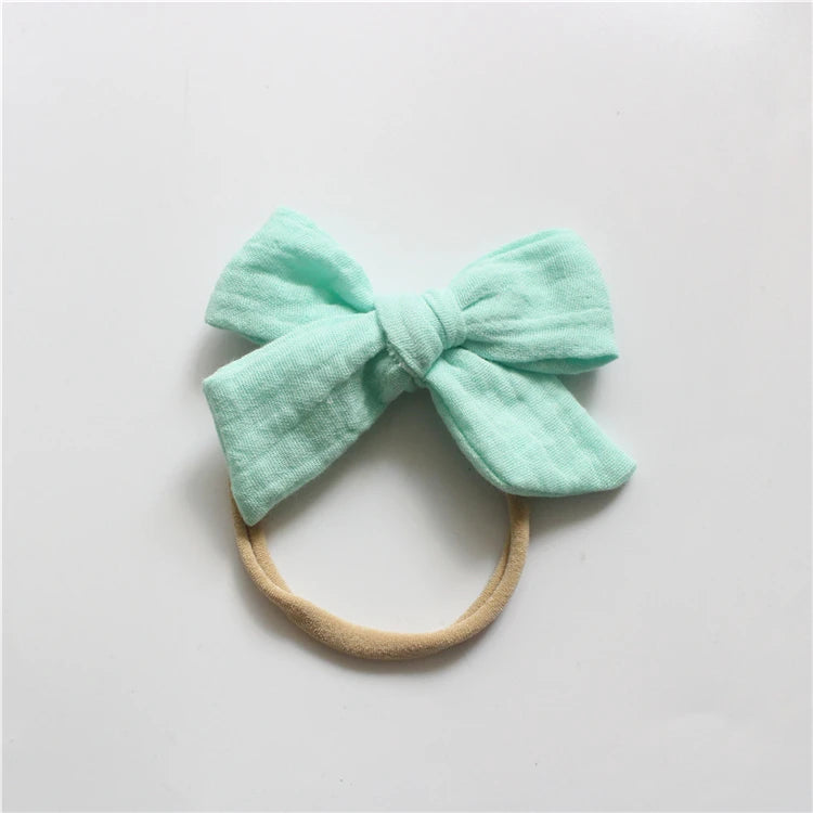 Mint green bow headband on a light gray background