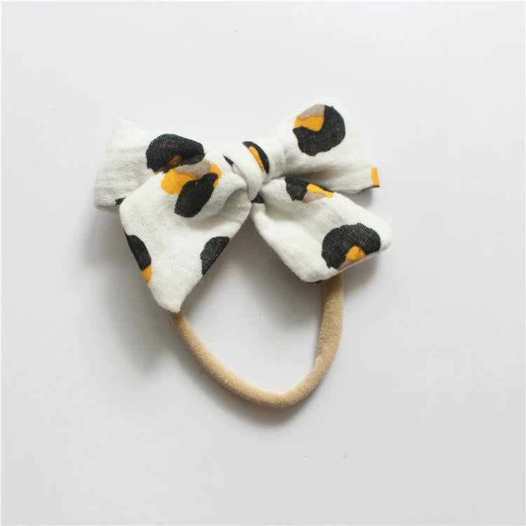 White headband with black and orange polka dot bow on a light gray background
