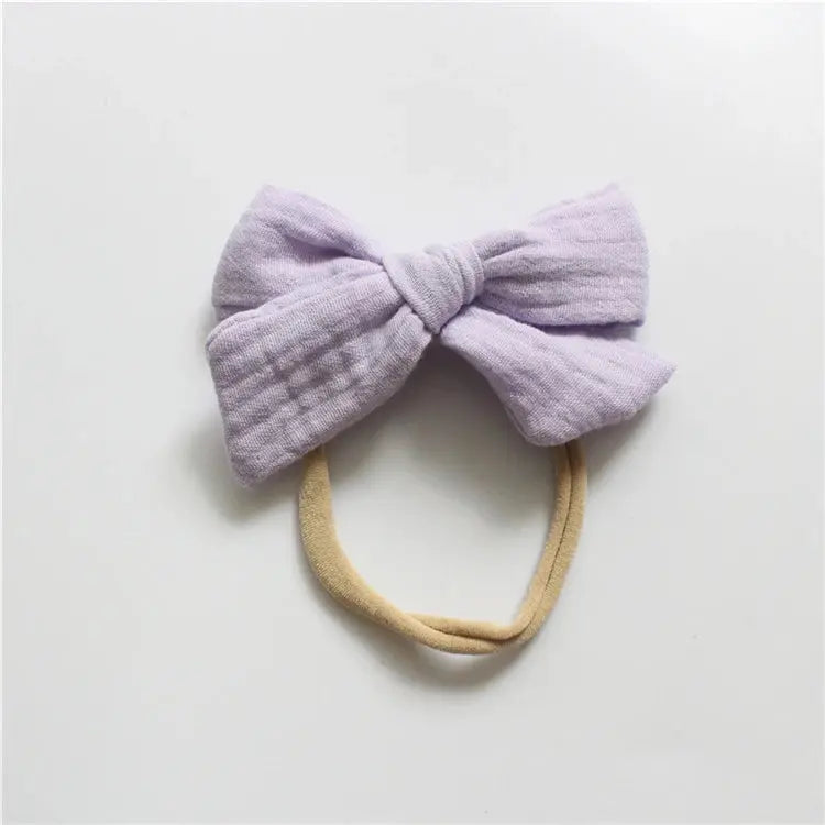 Lavender bow headband on a light gray background