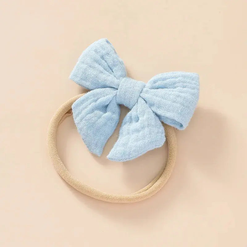 Light blue bow on a beige headband against a beige background