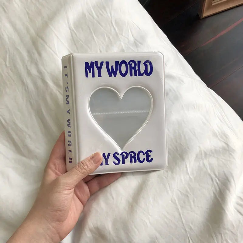 Book titled 'My World My Space' with a heart cutout held by a hand on a white surface.