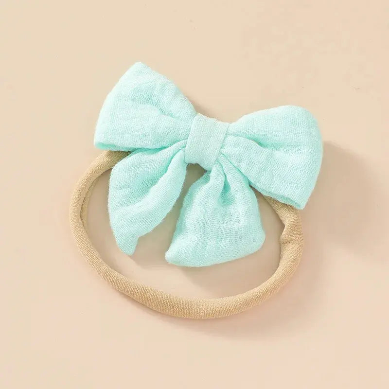 Mint green bow headband on a beige background