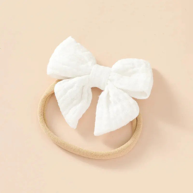 White headband with a large bow on a beige background