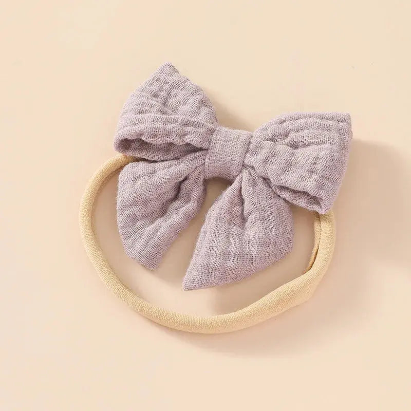 Baby headband with a textured purple bow on a beige background