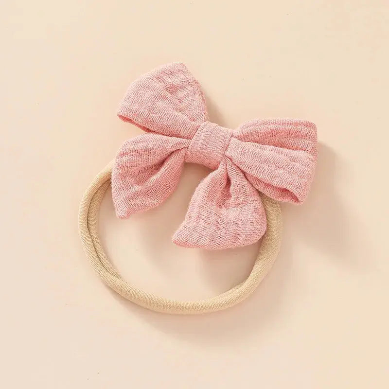 Pink bow headband on a beige background