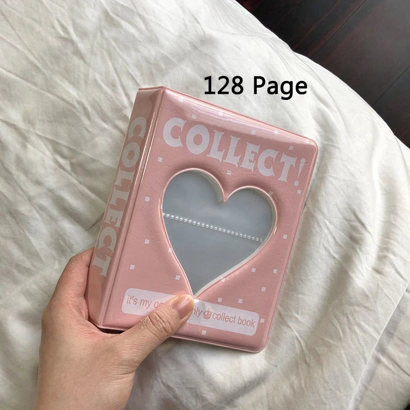 Pink photo album with heart design held by a hand on a white surface