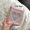Pink photo album with heart design held by a hand on a white surface