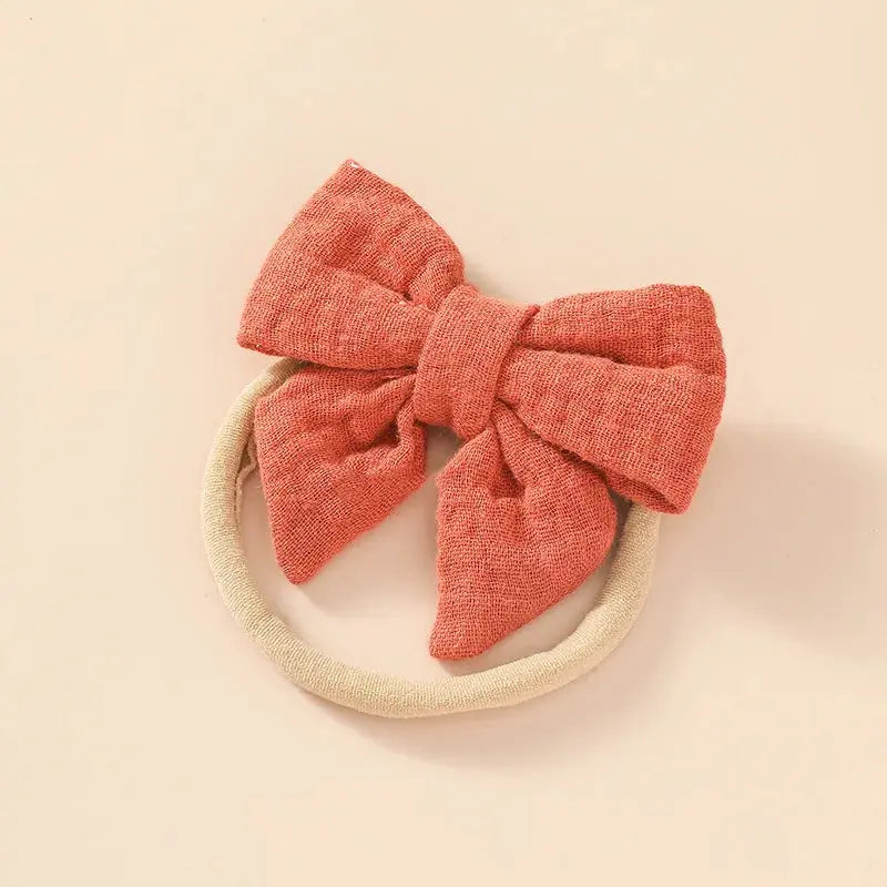Red textured bow hair accessory on a beige background