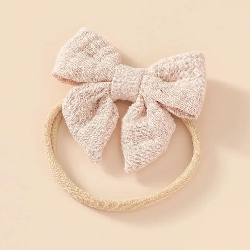Pink textured bow on a beige headband against a beige background