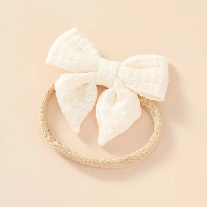 Cream-colored headband with a large bow on a beige background