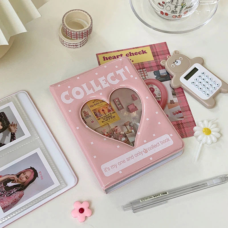 Pink 'Collect!' book with heart design on a white surface with stationery items.
