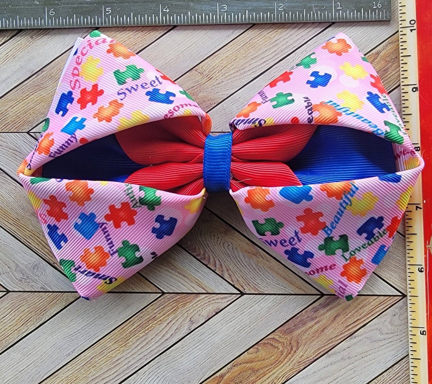 Colorful bow with puzzle piece pattern on a wooden surface with a ruler for scale.