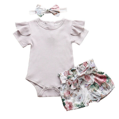 Baby outfit set with ruffled onesie, floral shorts, and headband on a white background
