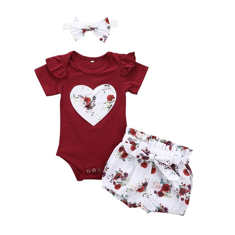 Baby outfit set with red romper, floral shorts, and headband on a white background