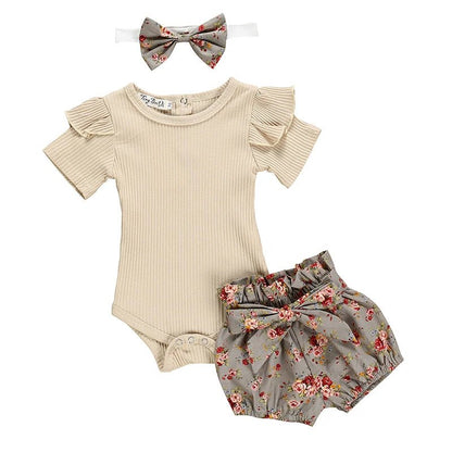 Baby outfit set with beige romper, floral bloomers, and headband on a white background
