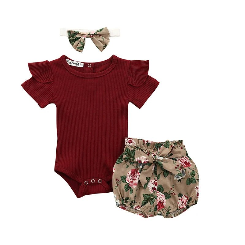 Baby outfit set with red romper, floral bloomers, and headband on a white background