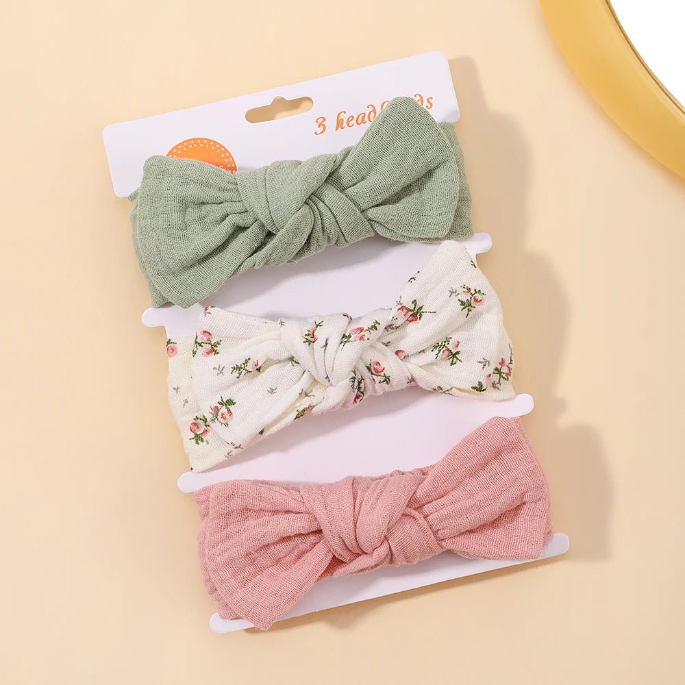 Set of three headbands with green, floral-patterned, and pink bows on a beige background.