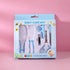 Baby grooming kit in retail packaging, including a brush, comb, nail clipper, and nail scissors, shown against a pink background.