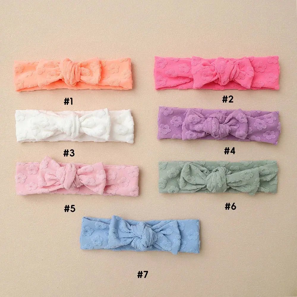 Set of seven colorful headbands with bows on a beige background