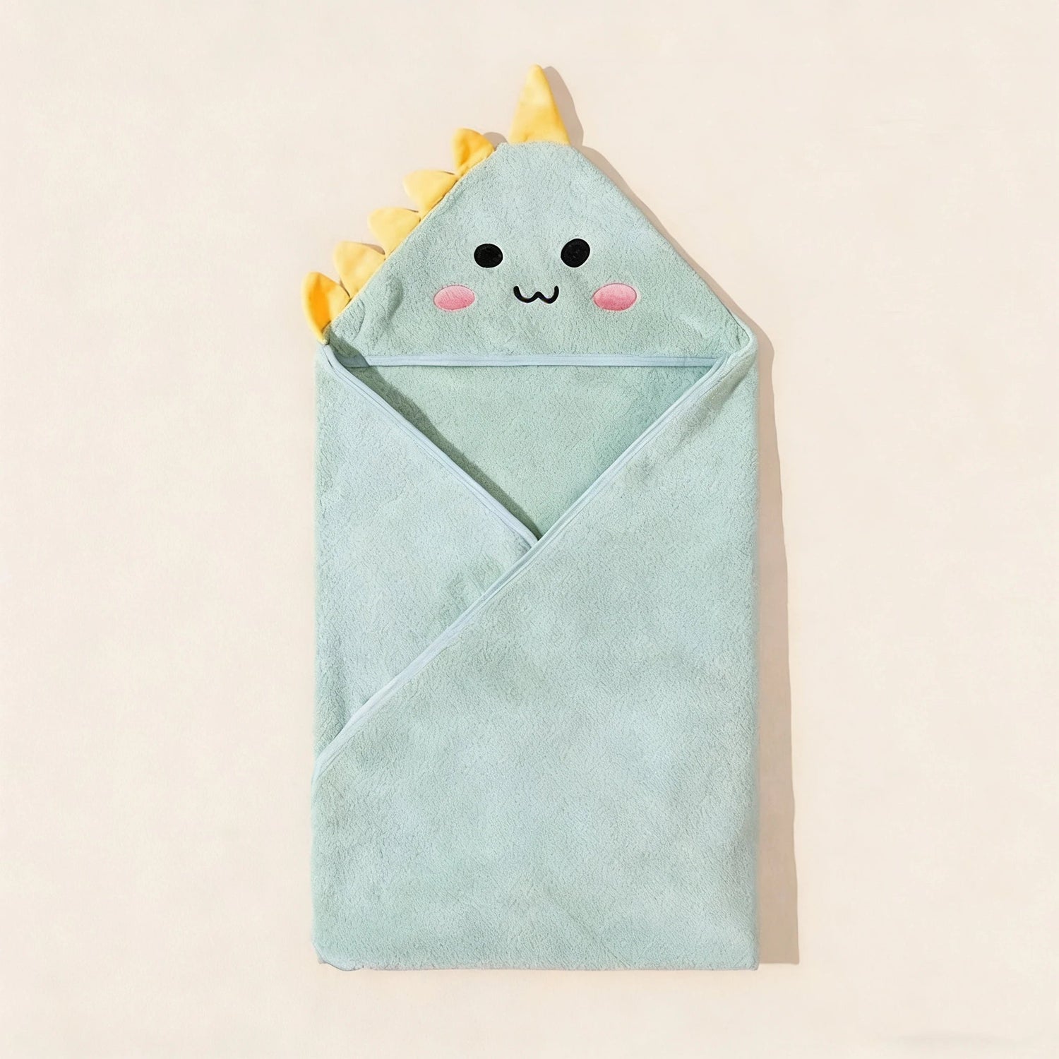 Light blue hooded towel with dinosaur design on a beige background