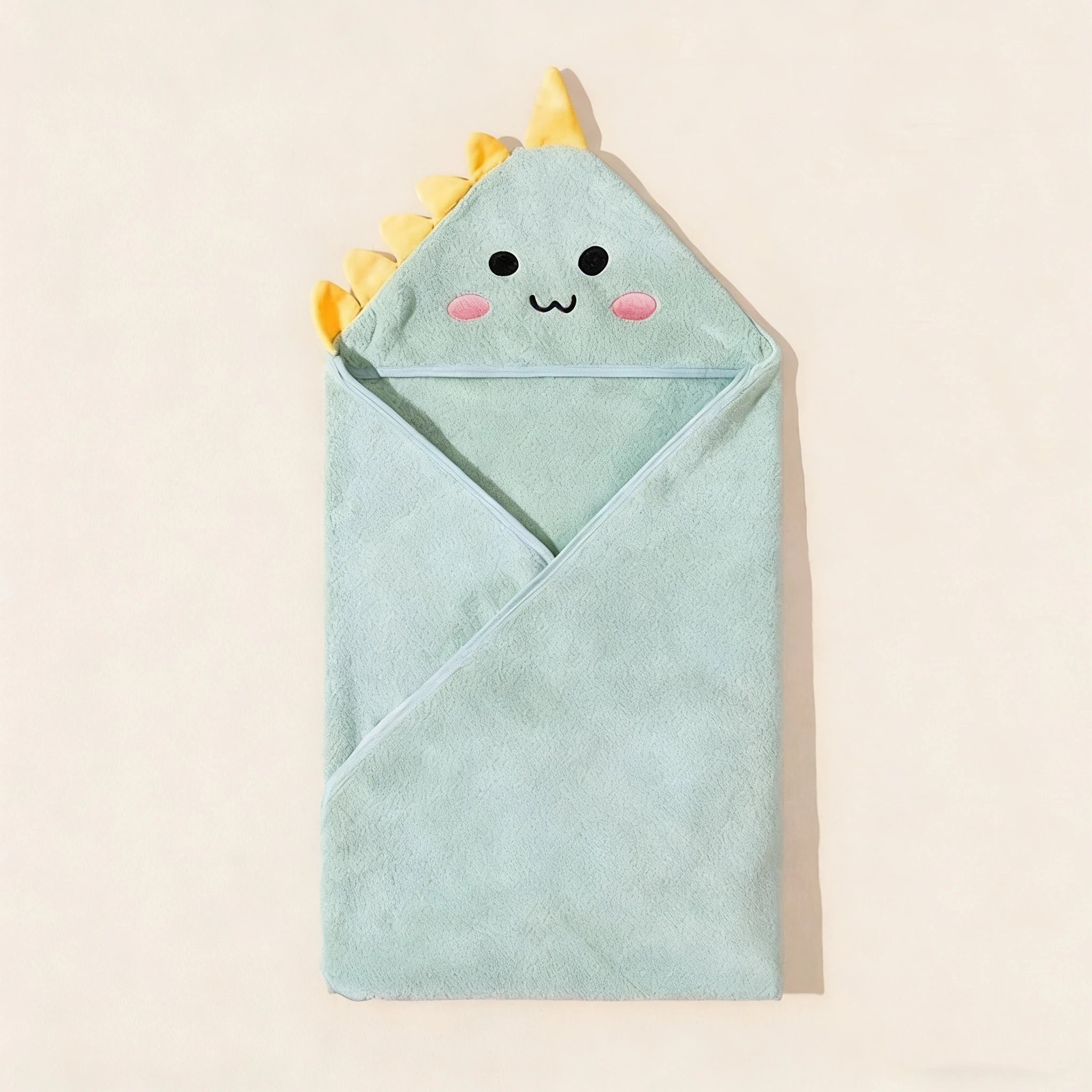 Light blue hooded towel with dinosaur design on a beige background