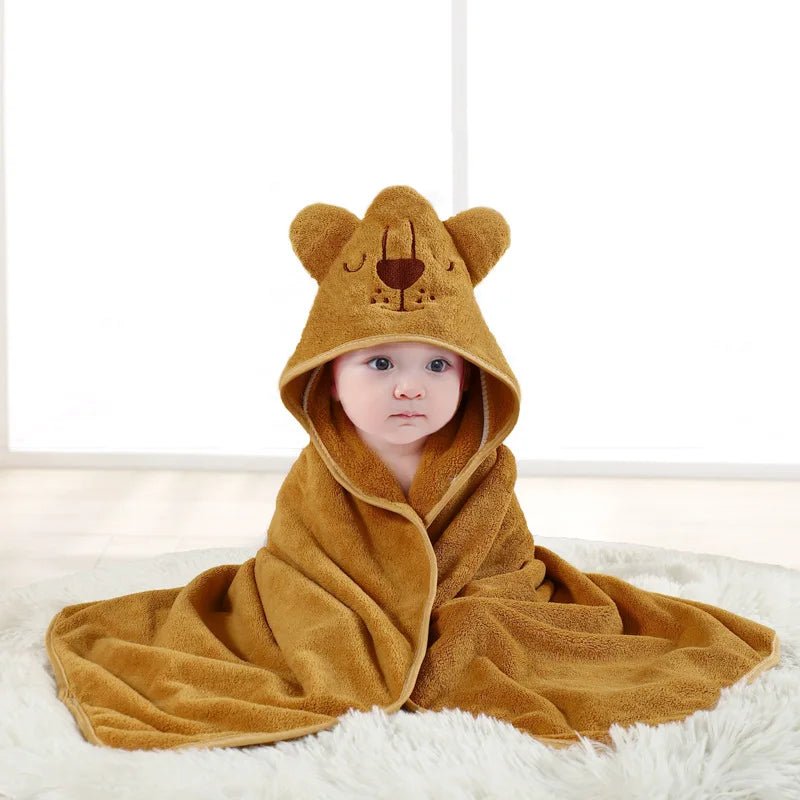 Baby wrapped in a brown bear hooded towel on a white surface