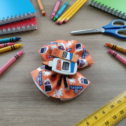 An orange hair bow featuring a Schreyvogel sticker design and Elmer&