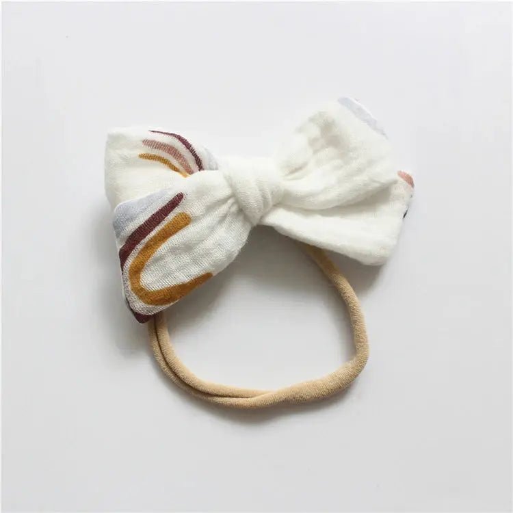 White bow headband with colorful pattern on a light gray background