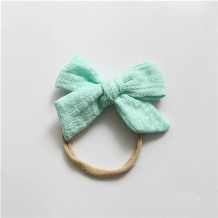 Mint green bow headband on a light gray background