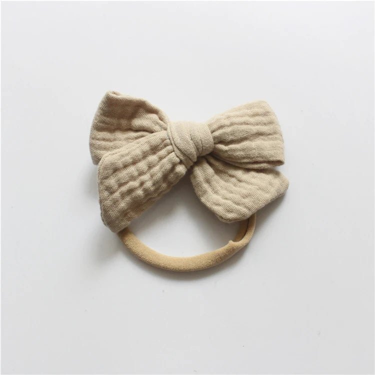 Beige knitted bow headband on a light gray background