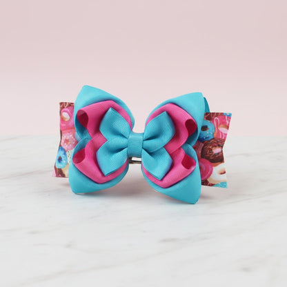 A two-tone hair bow made of grosgrain ribbon in turquoise blue and hot pink.