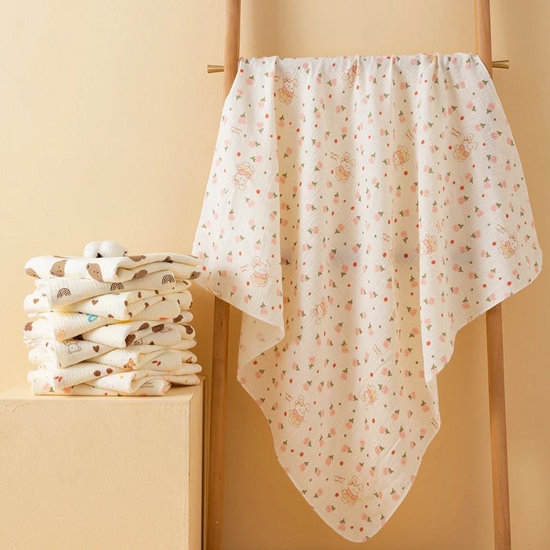 Stack of folded baby blankets with a floral pattern on a beige background