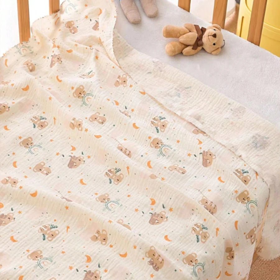 Baby crib with a soft, patterned blanket and a small teddy bear toy.
