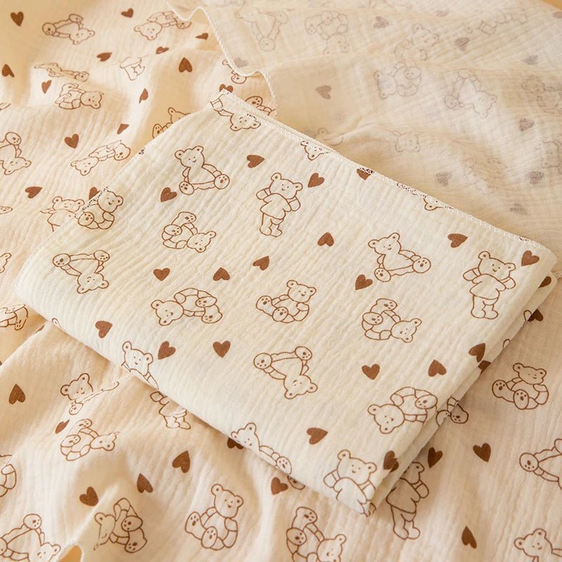 Baby blanket with teddy bear and heart pattern on a wooden surface
