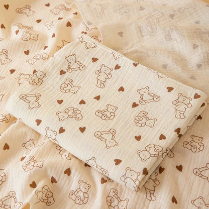 Baby blanket with teddy bear and heart pattern on a wooden surface