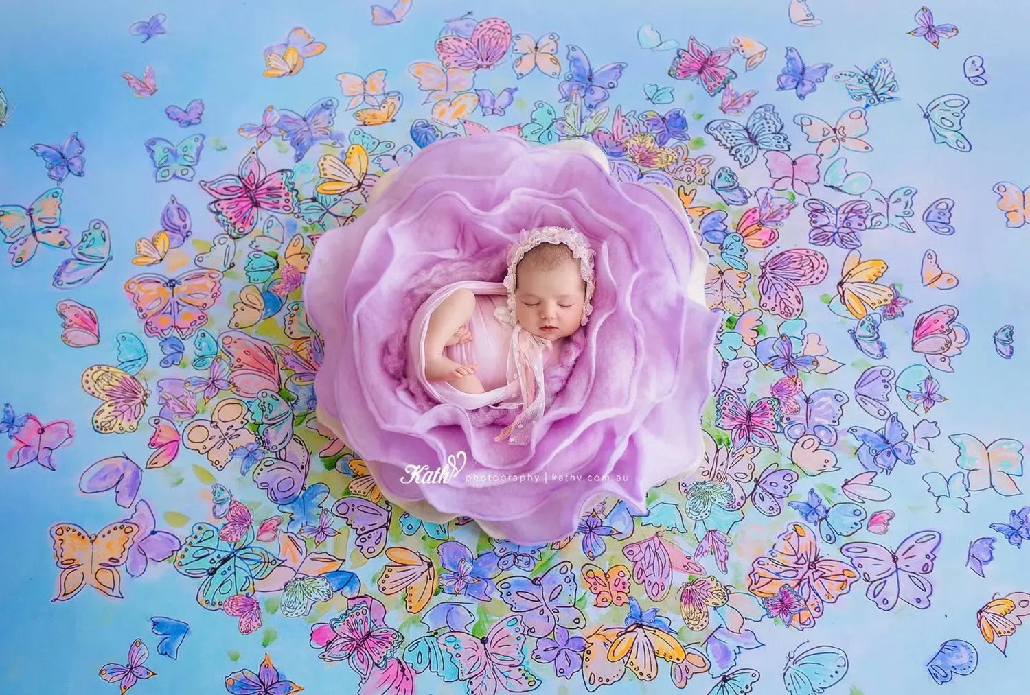 Newborn baby in a purple floral arrangement with colorful butterflies on a blue background
