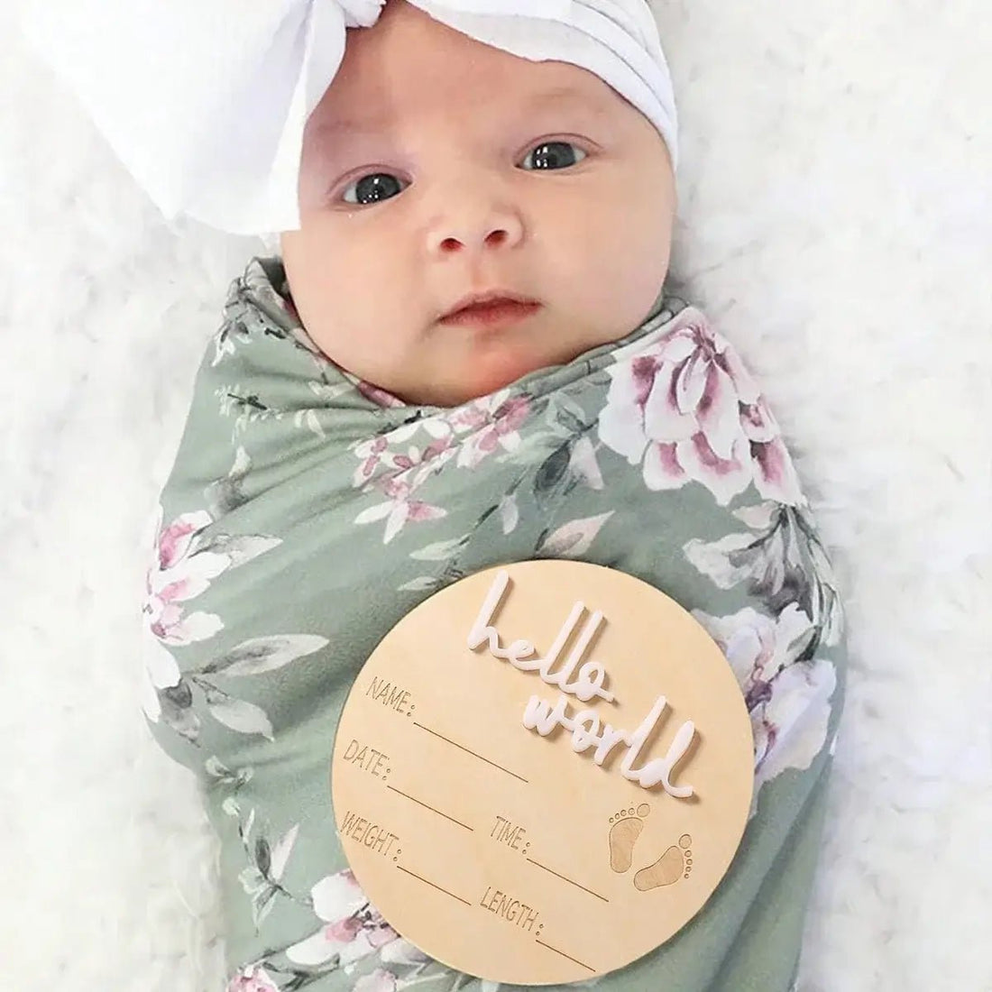 Newborn baby wrapped in a floral blanket with a &