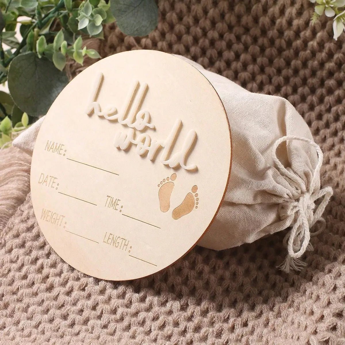 Wooden baby milestone card with engraved text on a textured surface