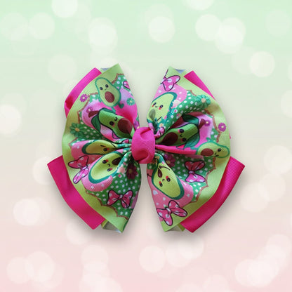 A colorful hair bow with a cartoon avocado pattern, pink trim, and a pink center