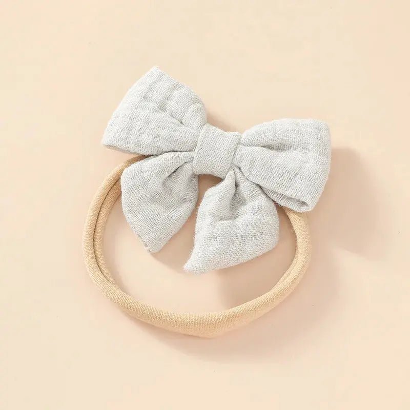Baby headband with a large gray bow on a beige background