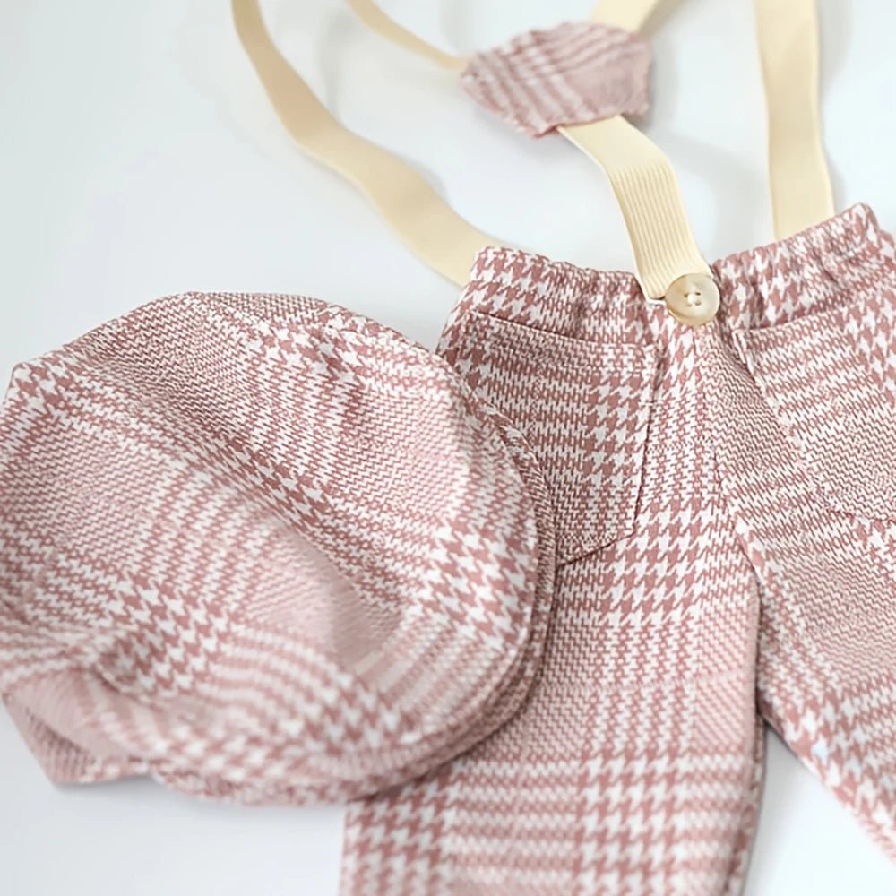 Pink plaid baby outfit with suspenders on a white background