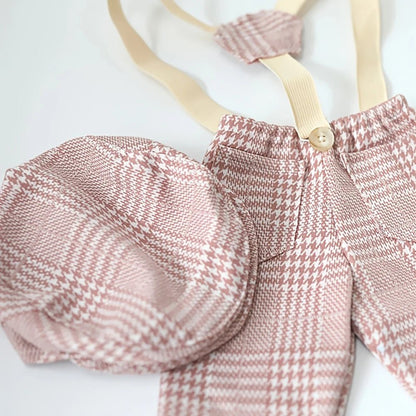 Pink plaid baby outfit with suspenders on a white background